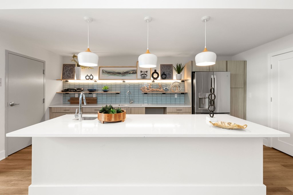 A modern kitchen with a white countertop and pendant lights.