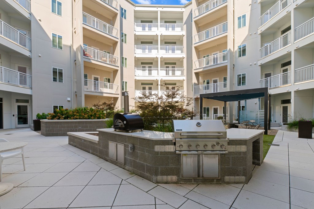 A patio with a grill and a bench in front of apartment buildings.
