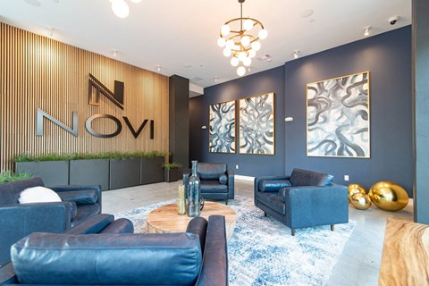 A modern living room with a blue couch and a wooden wall with the word "NOVI" on it.