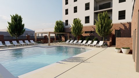 A pool surrounded by lounge chairs and trees.