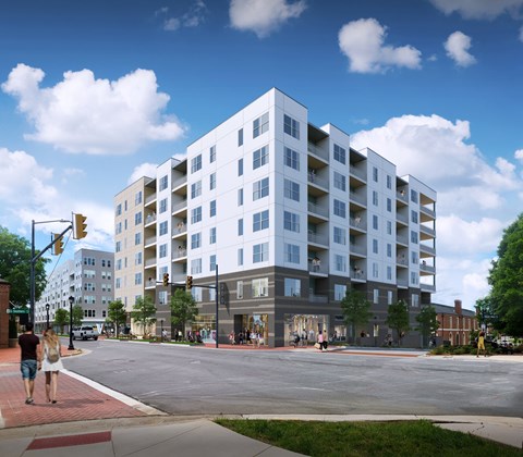 A large white building with a grey base is situated on a street corner with people walking on the sidewalk.