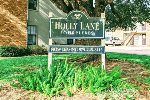 A sign for Holly Lane Fourplexes with a phone number for leasing.