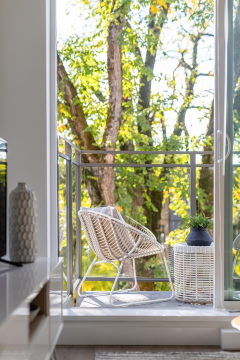 A white chair is on a balcony with a view of trees.