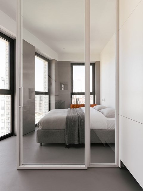 A bedroom with a bed and a large mirror on the wall.