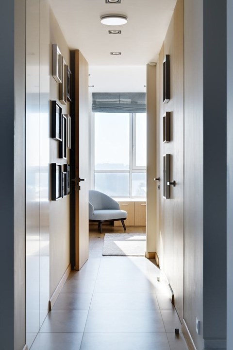 A long hallway with doors on both sides and a chair in the distance.