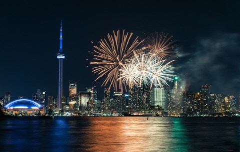 A city skyline with a lit up tower and fireworks in the sky.