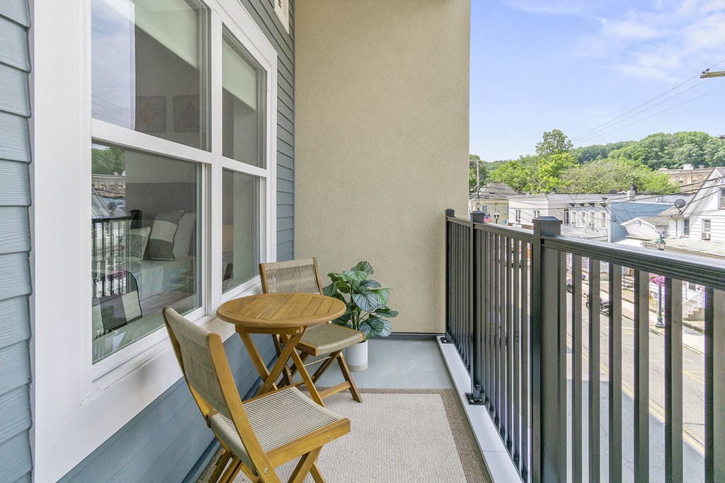A balcony with a table and chairs overlooking a street at 10 N. Main Apartments, Wharton, NJ