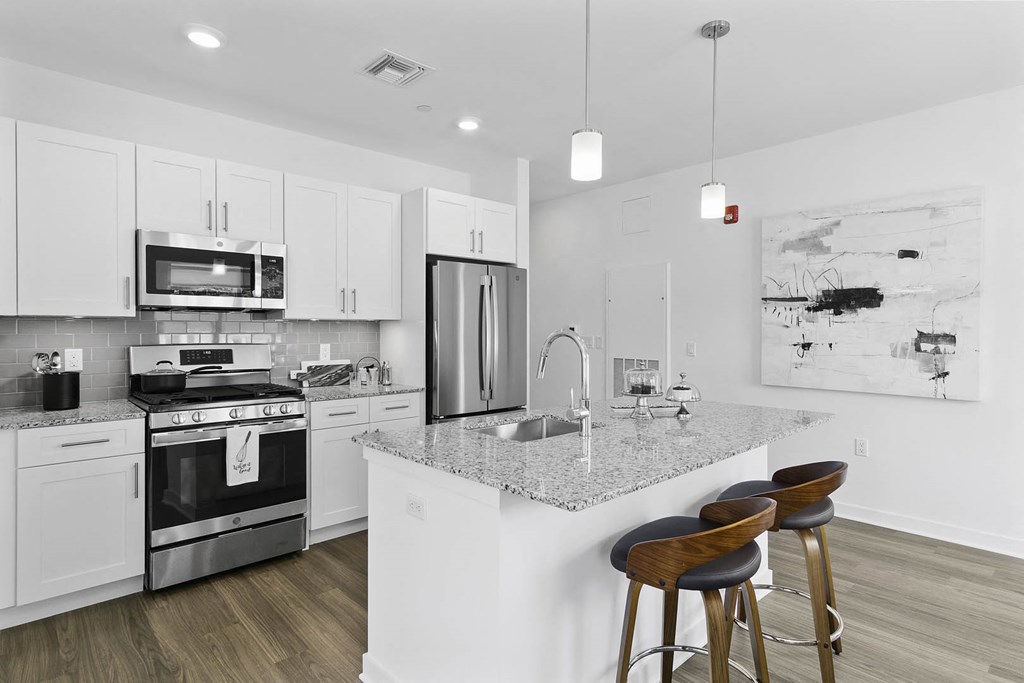A modern kitchen with a white island and stools at 10 N. Main Apartments, New Jersey, 07885