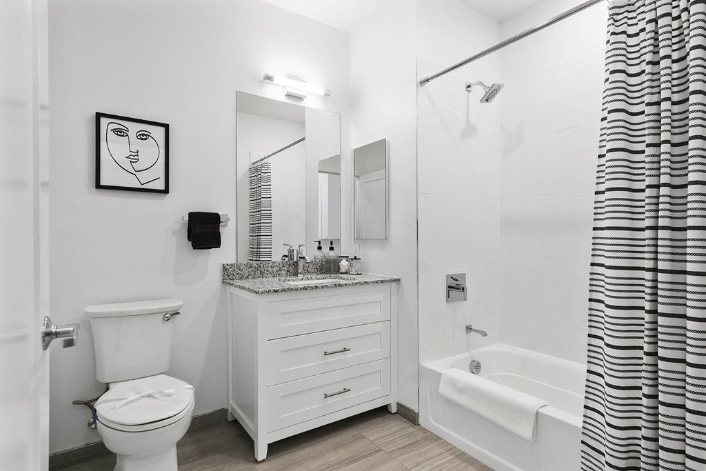 A white bathroom with a toilet, sink, and bathtub at 10 N. Main Apartments, Wharton 07885