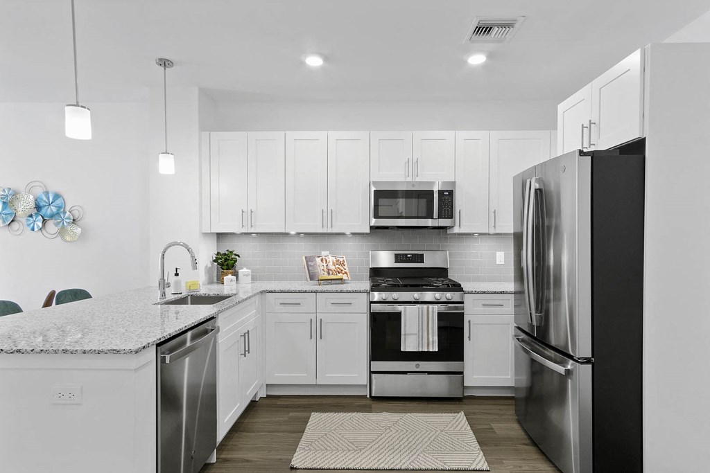 A modern kitchen with white cabinets and stainless steel appliances at 10 N. Main Apartments, New Jersey, 07885
