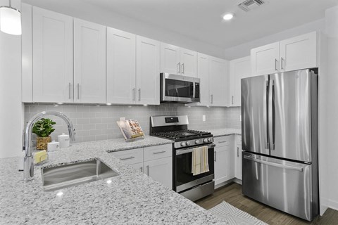 A modern kitchen with a stainless steel refrigerator and a granite countertop.
