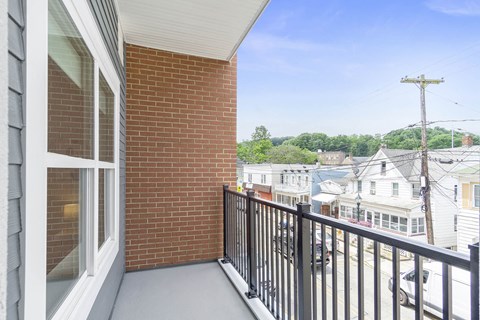 A balcony with a black railing and a brick wall.
