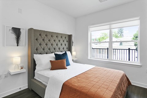 A bedroom with a large bed and a window overlooking a balcony.