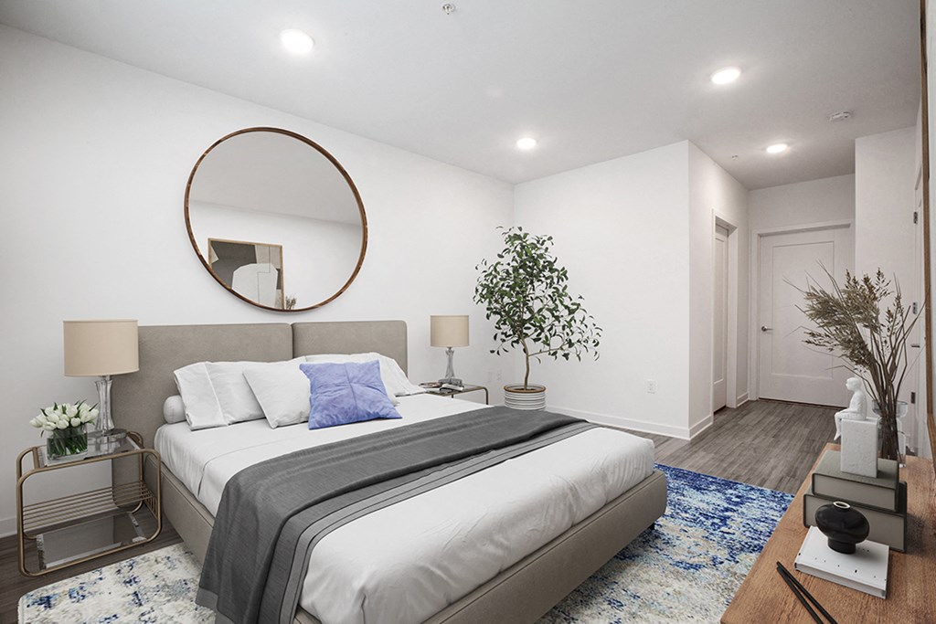 a white bedroom with a large bed and a mirror