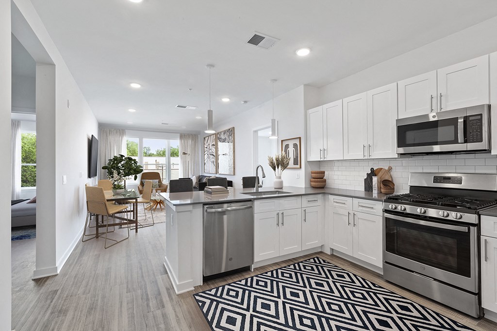 an open kitchen and living room with white cabinets and stainless steel appliances