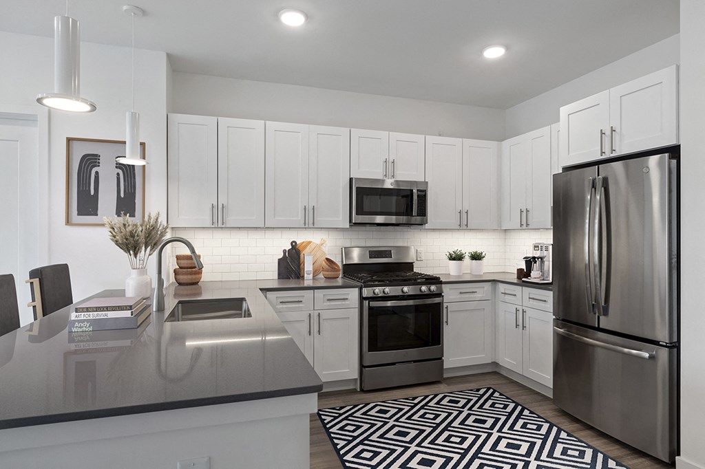 an apartment kitchen with stainless steel appliances and white cabinets
