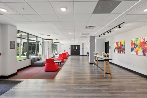 A long hallway with a red rug and chairs on the left side.