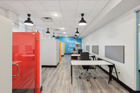 A room with a red door and a white wall with a blue banner that says Inspire Quietly Create.