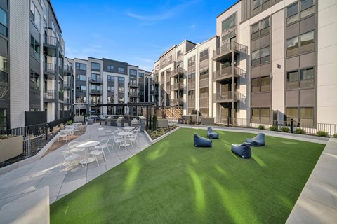 A sunny day at a modern apartment complex with a grassy courtyard.
