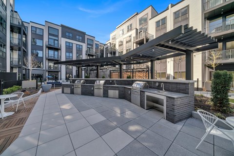 A modern outdoor kitchen area with a grill and seating area.