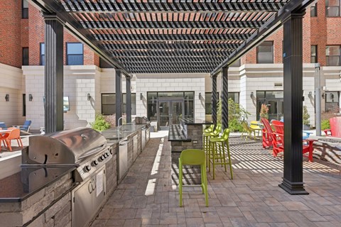 A patio with a grill and chairs.