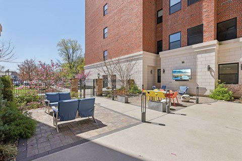 A brick building with a patio and chairs in front.