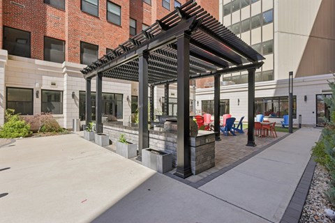 A patio with a black pergola and chairs.