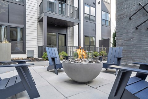 A modern patio with a fire pit and seating area.
