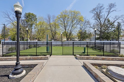 A black lamp post stands on a sidewalk in front of a black fence.