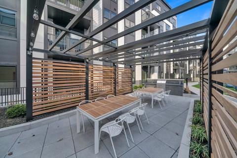 A patio with a table and chairs is surrounded by a metal fence.