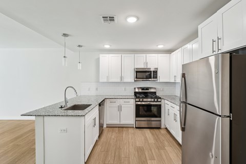 A modern kitchen with white cabinets and stainless steel appliances.