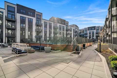 A modern courtyard surrounded by buildings with a bench and a table.