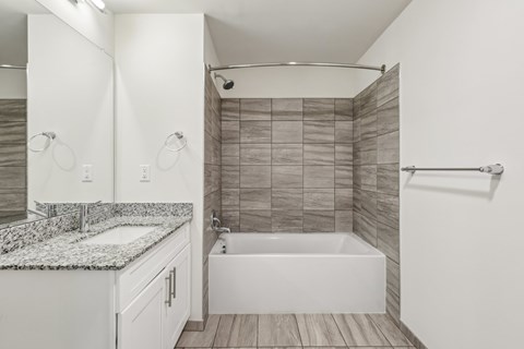 A white bathroom with a tub, sink, and mirror.