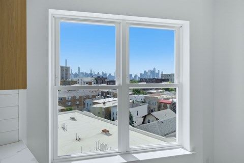 A white window with a view of a cityscape and buildings.