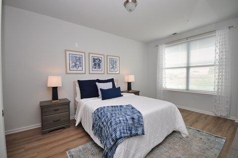 A bedroom with a bed, two lamps, and a window.