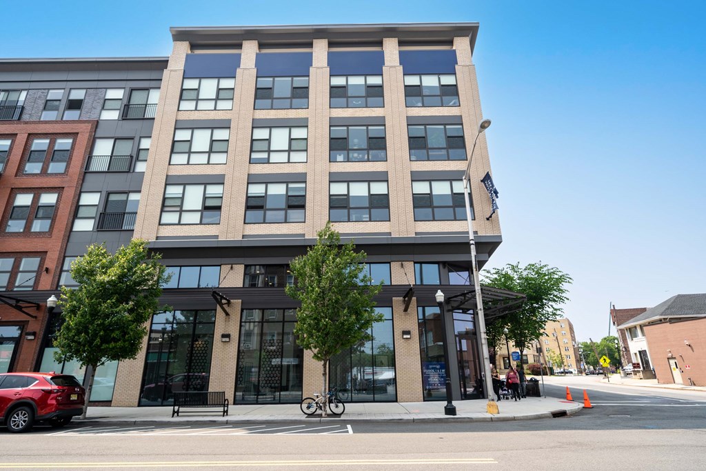 A modern building with a glass facade is situated on a street corner at Crossroads 389 Apartments, New Jersey, 07601
