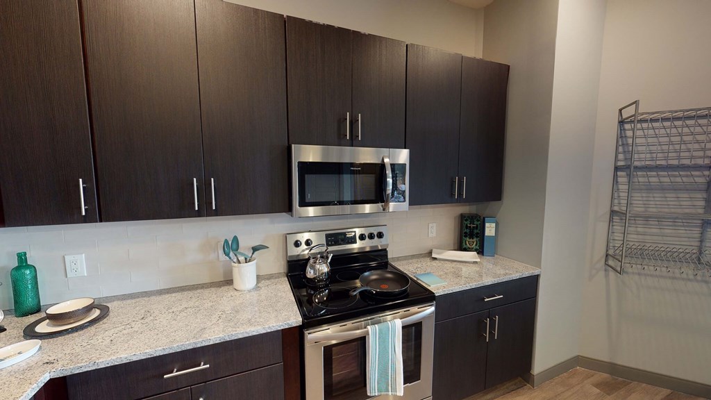 A kitchen with a stove top oven and microwave at Crossroads 389 Apartments, Hackensack