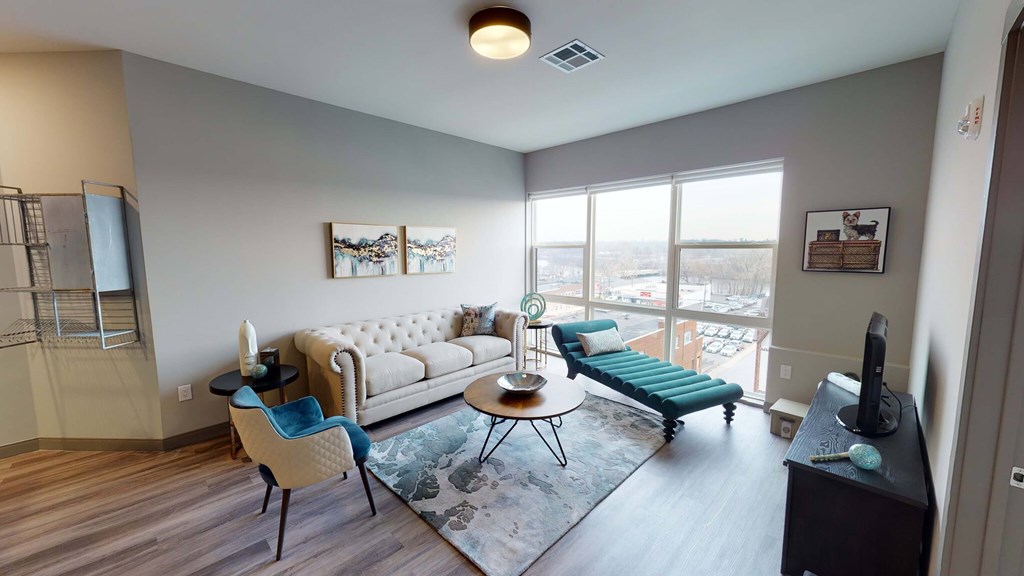 A living room with a white couch, a blue chair, and a television at Crossroads 389 Apartments, New Jersey