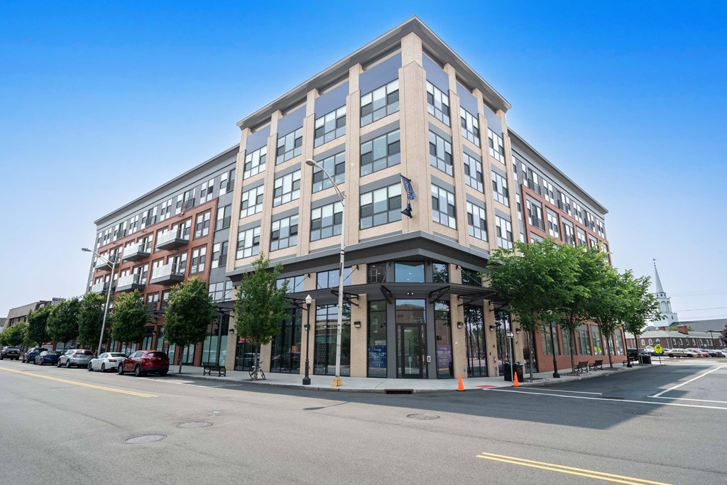 A modern multi-story building with a parking lot in front at Crossroads 389 Apartments, Hackensack, NJ