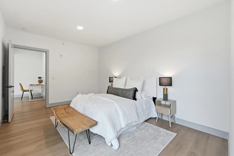 A bedroom with a bed, nightstand, and chair.