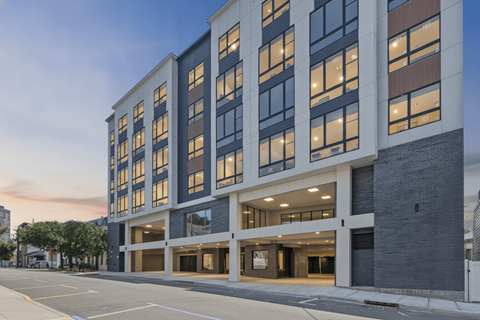 A modern building with a lot of windows and a parking lot in front.