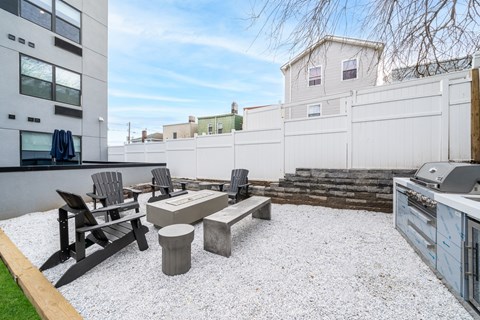 A patio with a table and chairs is surrounded by a white fence.
