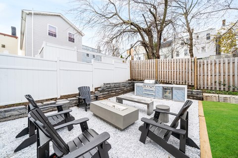 A backyard with a white fence and black furniture.