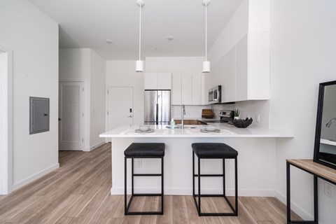 A kitchen with a white counter and bar stools.