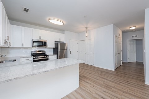 A kitchen with white cabinets and a wooden floor.