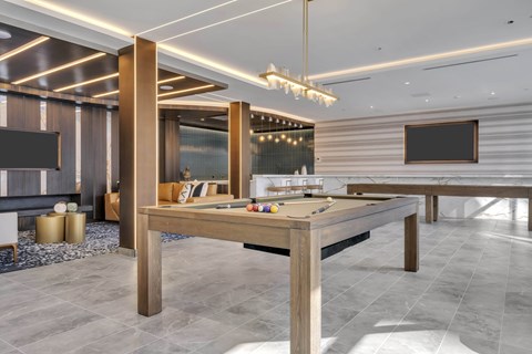 A billiard table in a room with a grey floor and a wooden table.
