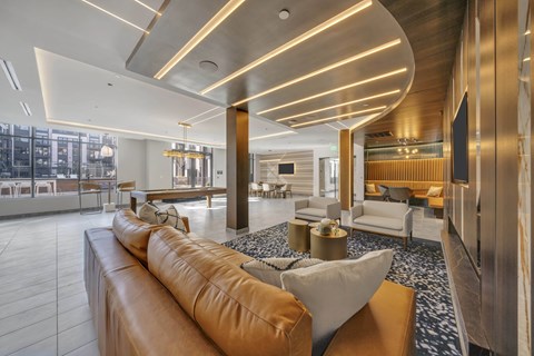 A modern living room with a long brown leather sofa and a coffee table in the center.
