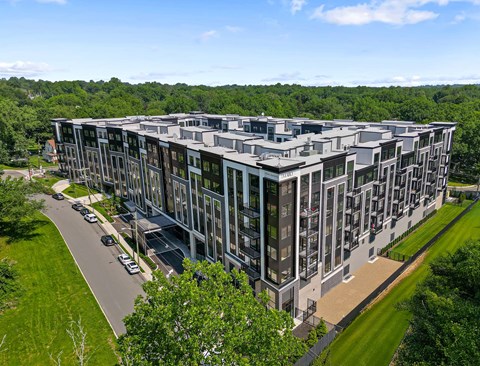 A modern multi-story building with a parking lot in front.