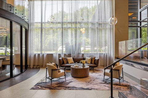 A modern living room with a glass wall and a large window.