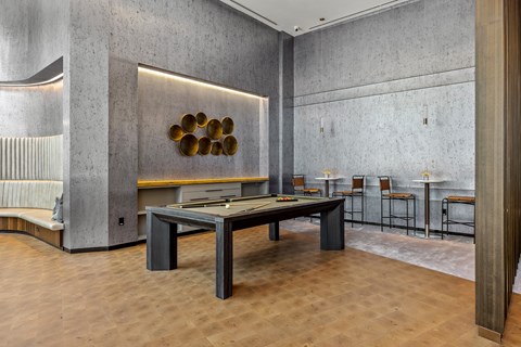 A room with a long table and chairs with a wall art.